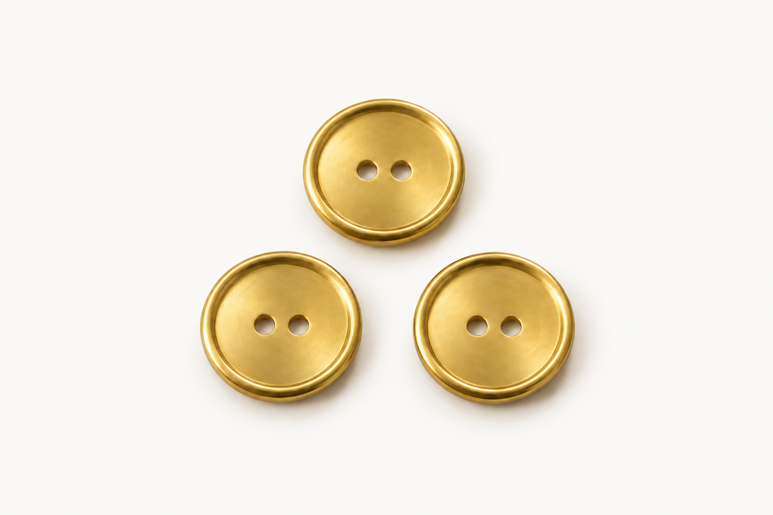 Drei goldfarbene Zweilochknöpfe