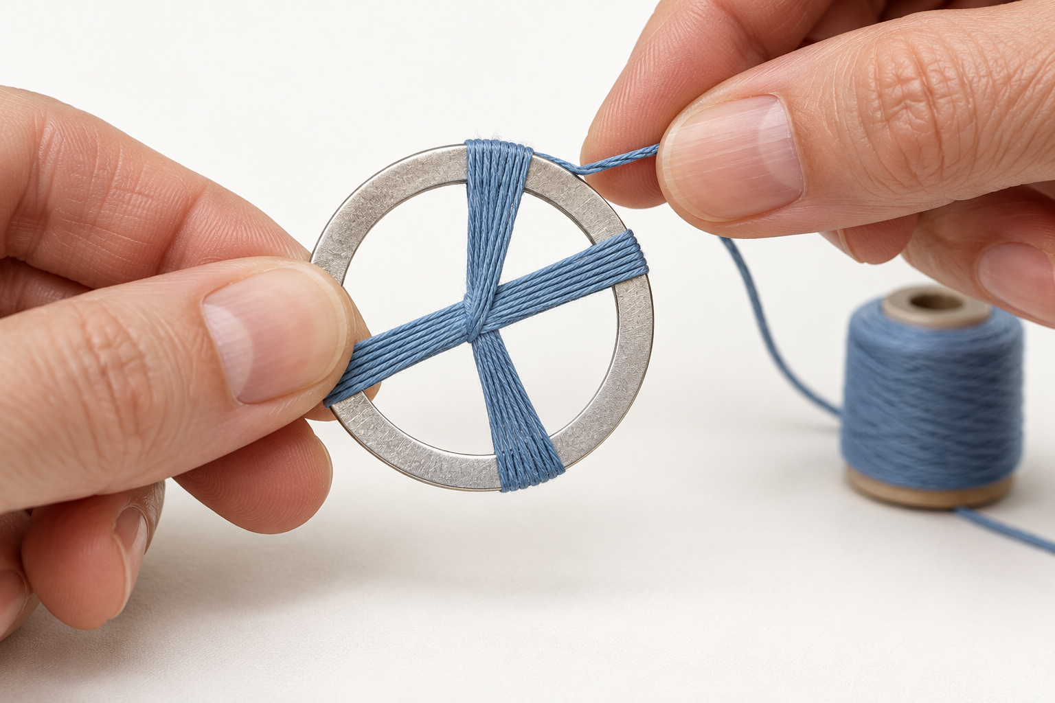 Hände umwickeln einen Ring mit blauem Garn